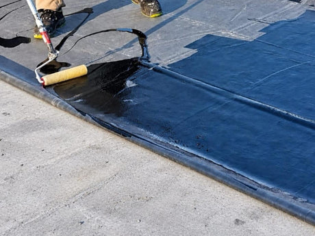 Kleber für EPDM-Dachfolie wird mit einer Spezail Kurzflor-Walze auf der Folie aufgetragen.